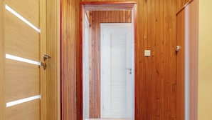 A hallway with wooden walls and a carpeted floor, leading to a white door at the end. - Perfect for Teams & Families: 3-Bedroom Flat, 7 Guests, Balcony, Close to Centre (Bratislava)