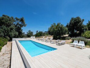 A rectangular swimming pool with a wooden deck, surrounded by white lounge chairs and greenery. - Olea Green Studio 1, Tavira, Algarve (Querença)