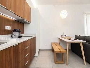 Eine moderne Küche mit Holzausbau, einer integrierten Kaffeemaschine, einer weißen Arbeitsplatte und einer hängenden Pendelleuchte.