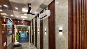 A modern hotel lobby with marble flooring, a ceiling fan, recessed lighting, and a reception area with a glass door. - Taj Pride Inn (Amritsar)