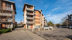 Um edifício residencial com vários andares, varandas, área de estacionamento e céu limpo.