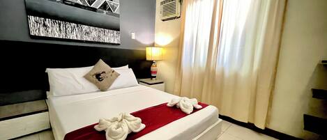 A hotel room with a bed, a nightstand, a lamp, and a wall with geometric patterns.