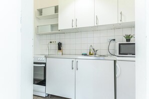 Een moderne keuken met witte kastjes, een magnetron en een oven.