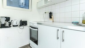 A modern kitchen with white cabinets, a built-in oven, a coffee maker, a toaster, and a window above the sink. - Elegant Spacious 2BR City Center Stay (Vienna)