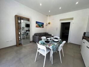 A compact living space with a dining area, kitchenette, and a gray sofa. - Al Vecchio Cinema new home near Otranto and Torre dell'Orso (Martano)