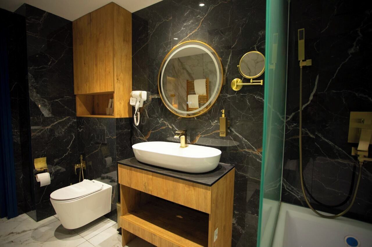 A modern bathroom with a freestanding bathtub, a vanity with a large mirror, and a marble backsplash.