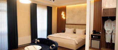 Una habitación de hotel moderna con una cama grande, un escritorio pequeño, una silla y un armario.