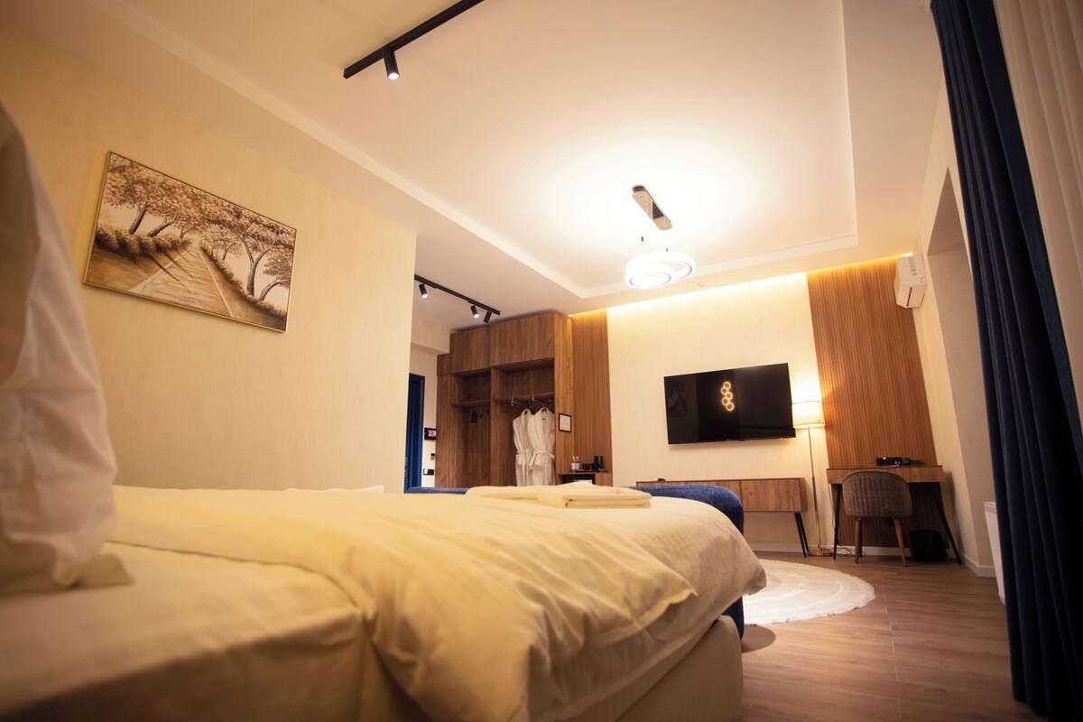 Een moderne hotelkamer met een groot bed, een bureau, een televisie en een schilderij aan de muur.