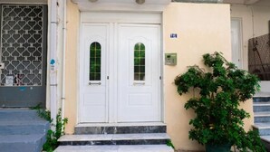 A building entrance with two white doors, a small potted plant, and a number 16 sign. - Spacious & Modern Retreat with Sun Terrace in Neos Kosmos, Athens (Athina)