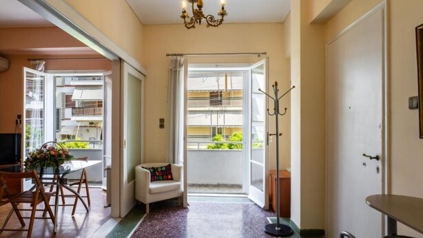 A hotel room with a dining area, a balcony with a view, and a coat rack. - Spacious & Modern Retreat with Sun Terrace in Neos Kosmos, Athens (Athina)