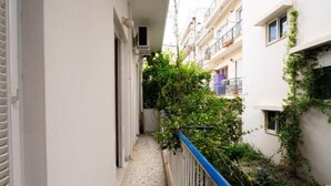 A narrow balcony with a blue railing, surrounded by white buildings with balconies and some greenery. - Spacious & Modern Retreat with Sun Terrace in Neos Kosmos, Athens (Athina)