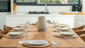 A dining table set for six with plates, glasses, and cutlery, a large vase centerpiece, and a window with a view of greenery. - Villa Hamza with private pool - My Rental Homes (Oulad Ikhia)
