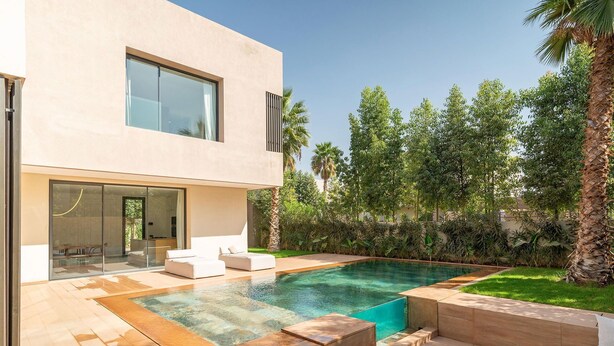 A modern house with a swimming pool, outdoor seating, and lush greenery. - Villa Hamza with private pool - My Rental Homes (Oulad Ikhia)