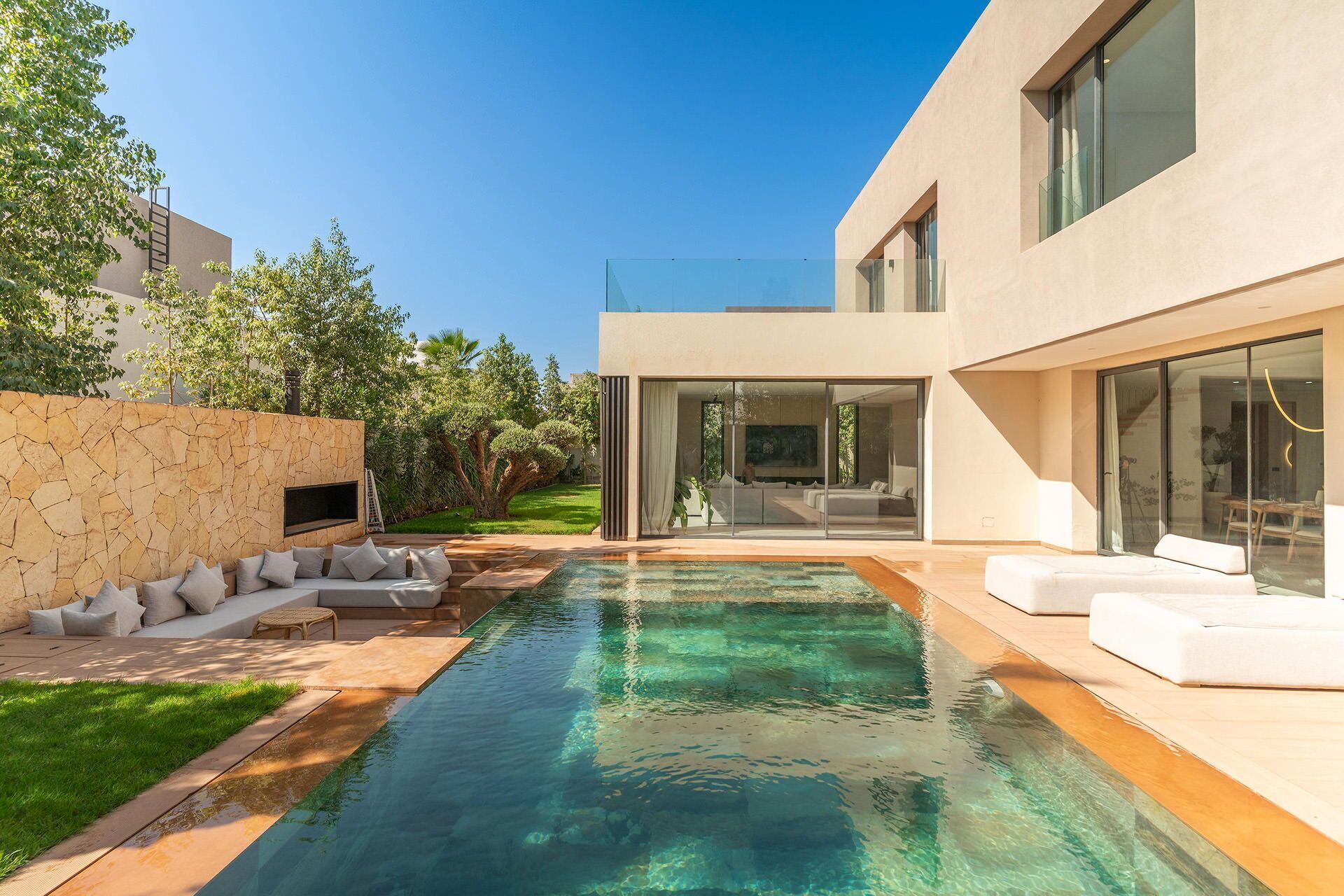 A modern house with a swimming pool, outdoor seating, and a glass-enclosed living area.