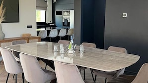 Ett modernt matområde med ett stort ovalt bord, sex stolar och en hängande lampa.
