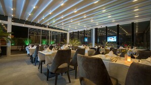 Ein Restaurant mit modernem Deckenstil, großen Fenstern und einem gut beleuchteten Innenraum.