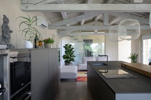 A modern kitchen with a built-in oven, a dining area with a white sofa, and a large potted plant. - Villa Terontola Luxury by MMega (Cortona)