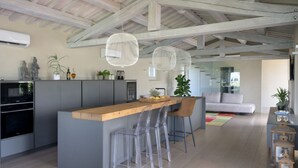 Una cocina moderna con una isla de madera, taburetes de bar e iluminación colgante.