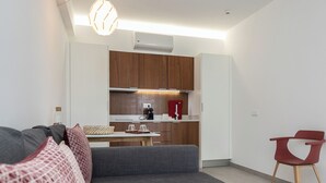 En moderne stue med en grå modulsofa, et lille spisebord og en rød lænestol.