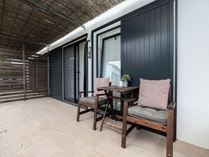 A patio with a wooden table and two chairs, a potted plant, and a sliding glass door. - Olea Black Studio 2, Tavira, Algarve (Querença)