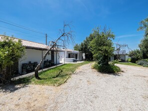 A row of white buildings with a gravel path leading to a covered outdoor seating area. - Olea Black Studio 2, Tavira, Algarve (Querença)
