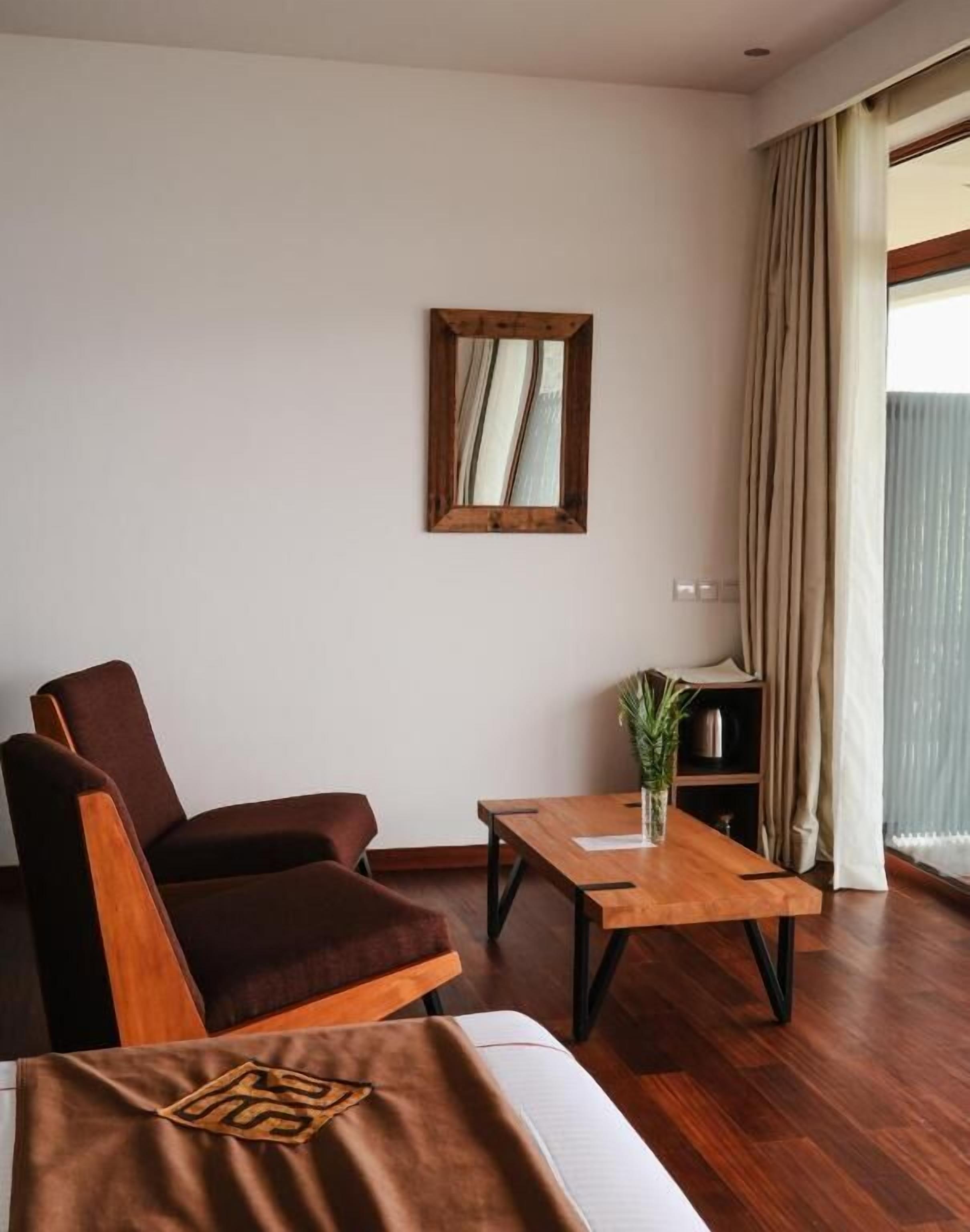A modern hotel room with a wooden sofa, a small wooden table, and a mirror on the wall.