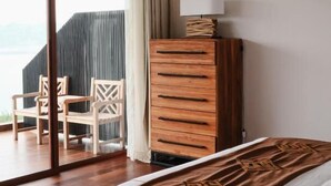 Een hotelkamer met een bed, een houten dressoir, een stoel en uitzicht op de omgeving.