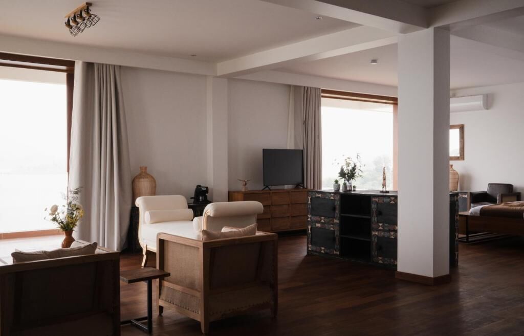 A spacious living room with a large window, a television, and a wooden cabinet.