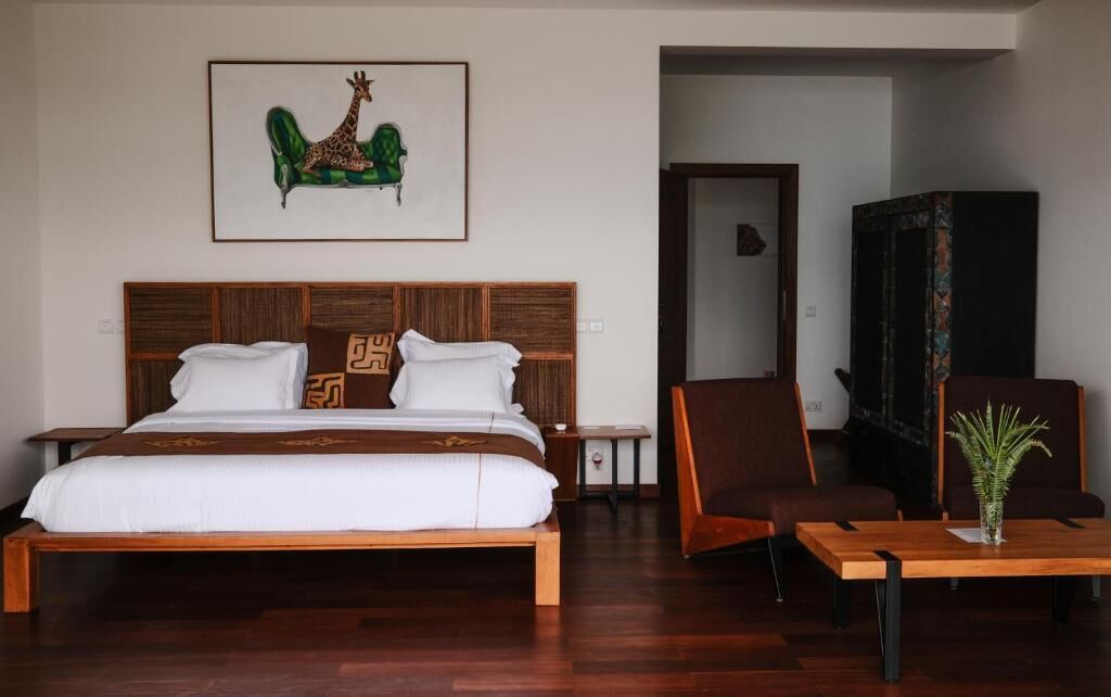 Un dormitorio con una cama de madera, una silla, una mesa y un cuadro en la pared.