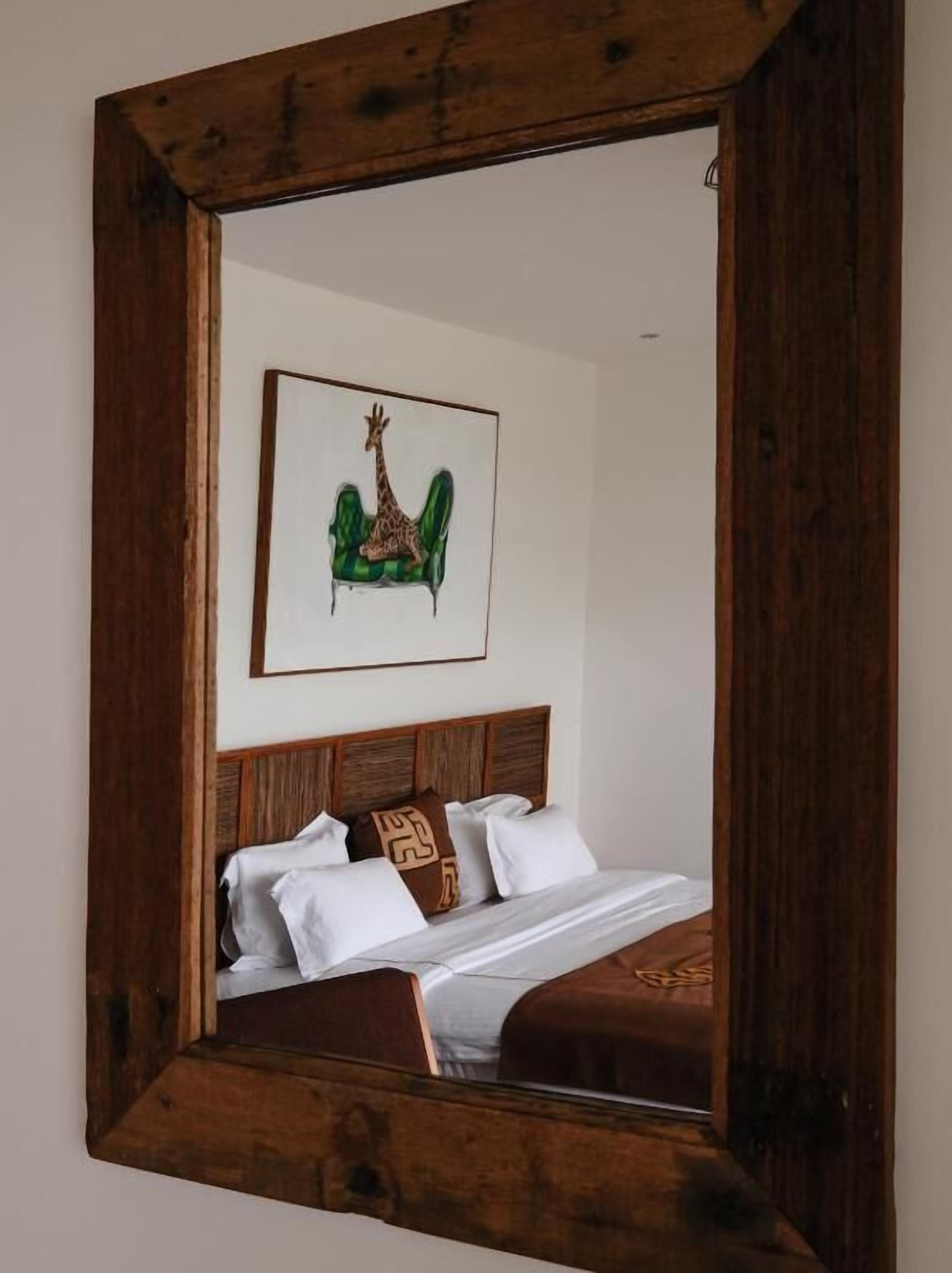 A bed with a wooden headboard, white bedding, and a single pillow with a geometric design.