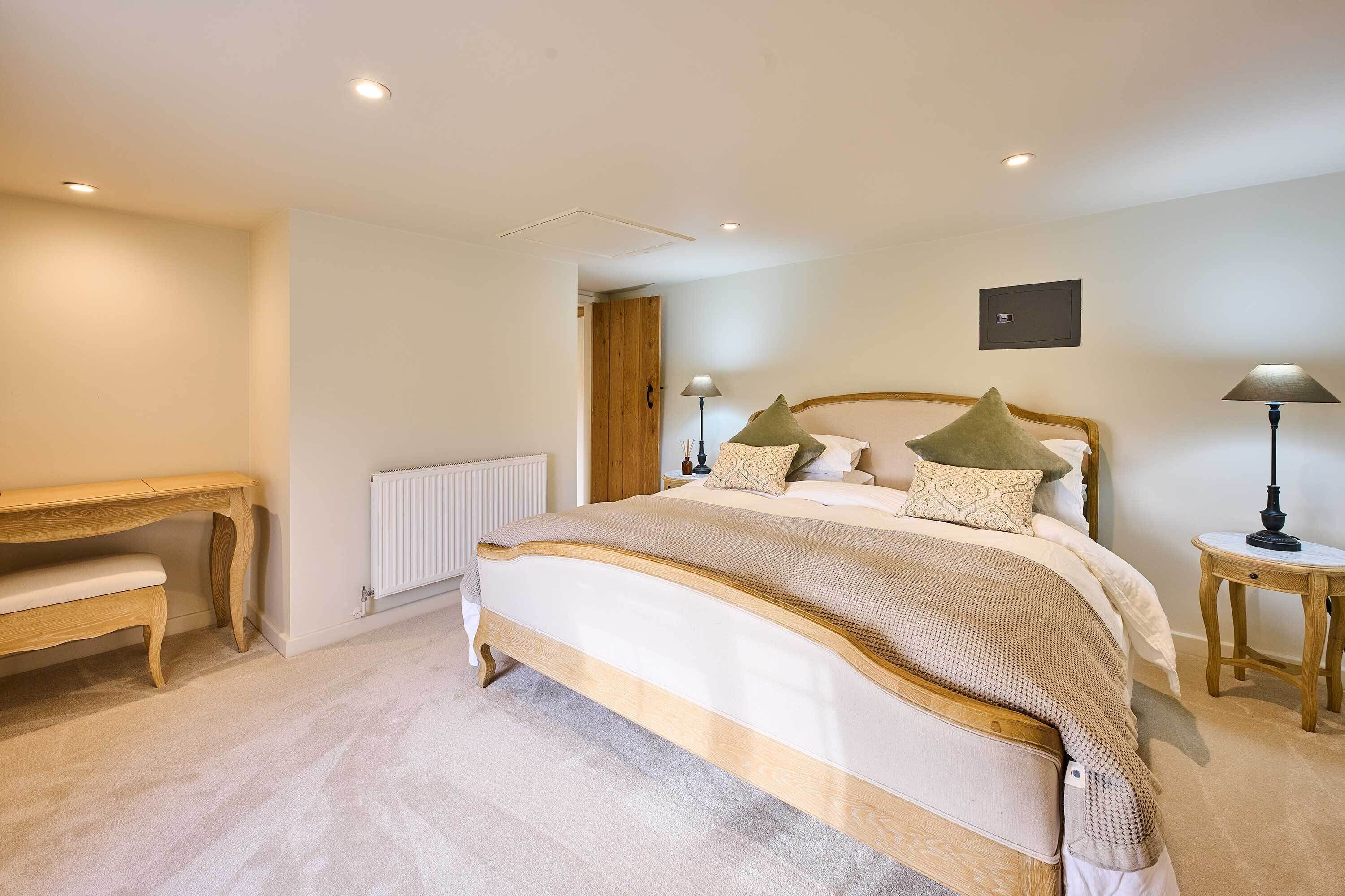A bedroom with a large bed, bedside tables, a wooden bench, and a radiator.