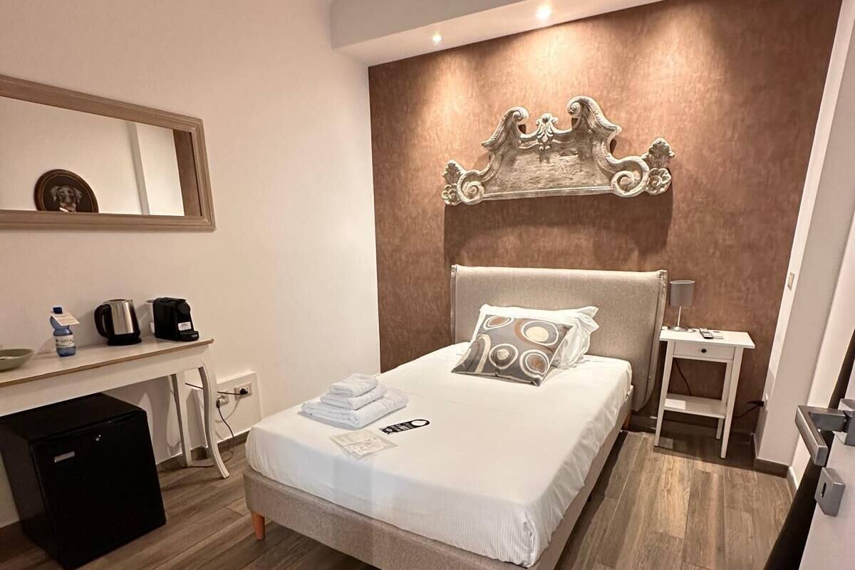 A modern bedroom with a bed, bedside table, and a small desk with a chair.