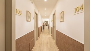 A hallway with doors numbered 103 and 104, leading to a room with a bed and a nightstand. - Popolo Rooms&Suites (Rome)