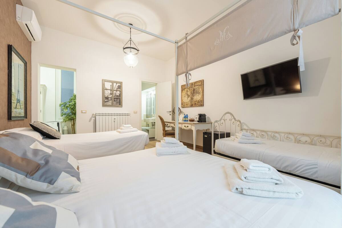 A hotel room with two beds, a desk, a chair, a TV, and a window with a view.