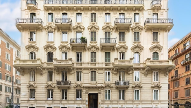 A multi-story building with a symmetrical facade, numerous balconies, and a central entrance. - Popolo Rooms&Suites (Rome)