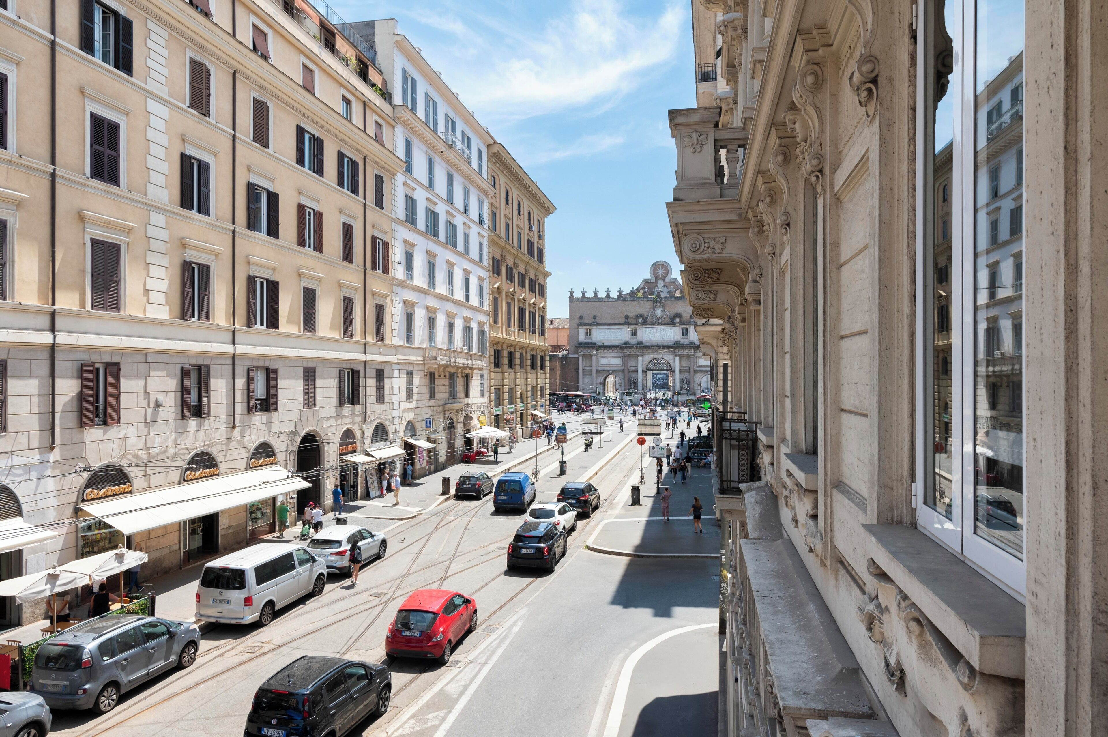 Una calle con edificios históricos, un tranvía y automóviles estacionados.