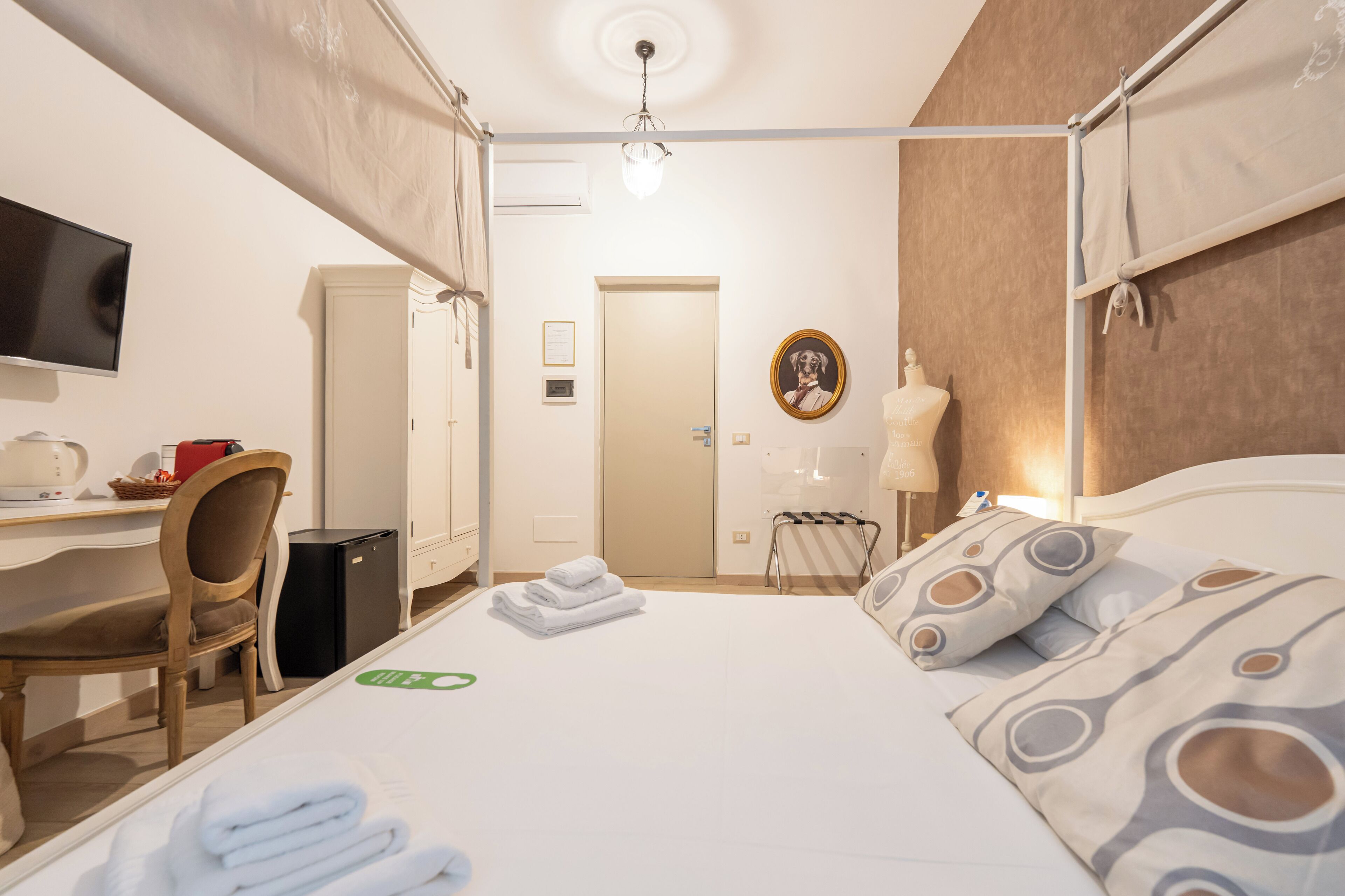 Ein Hotelzimmer mit Bett, Schreibtisch, Sessel, Fernseher und Kleiderschrank.