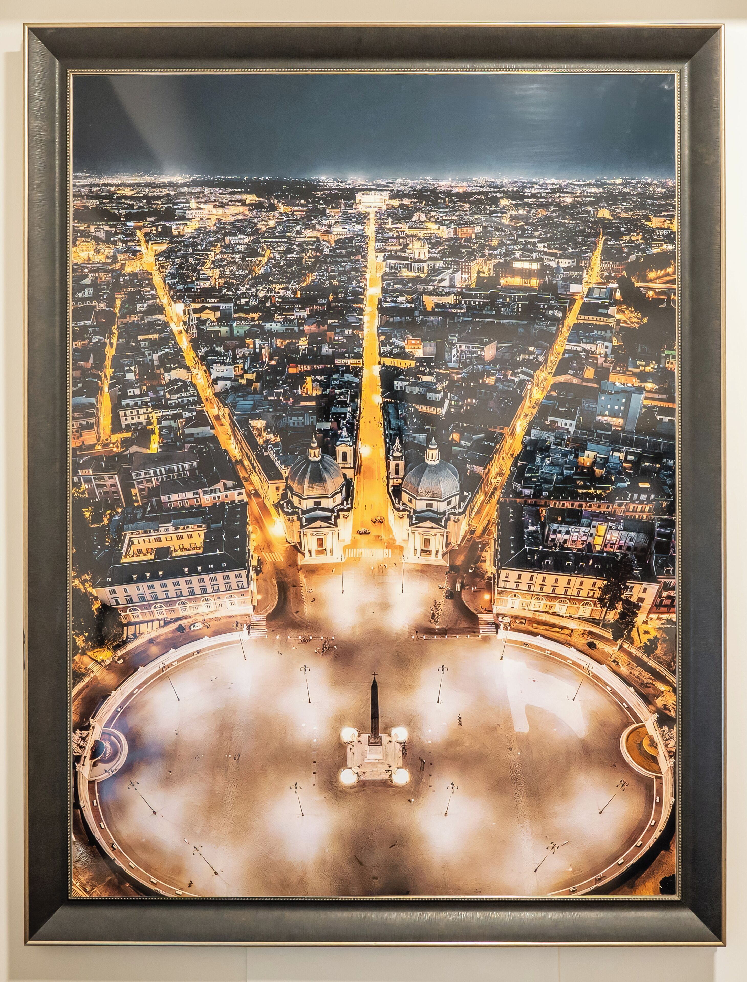 A framed aerial view of a cityscape with a prominent bridge structure and a central plaza.