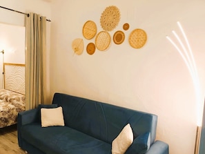 Ein Zimmer mit blauer Couch, einem gemusterten Bett und Wanddekoration.