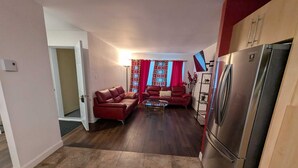 Ett kompakt bostadsutrymme med ett litet kök, en soffa, ett soffbord och ett kylskåp.