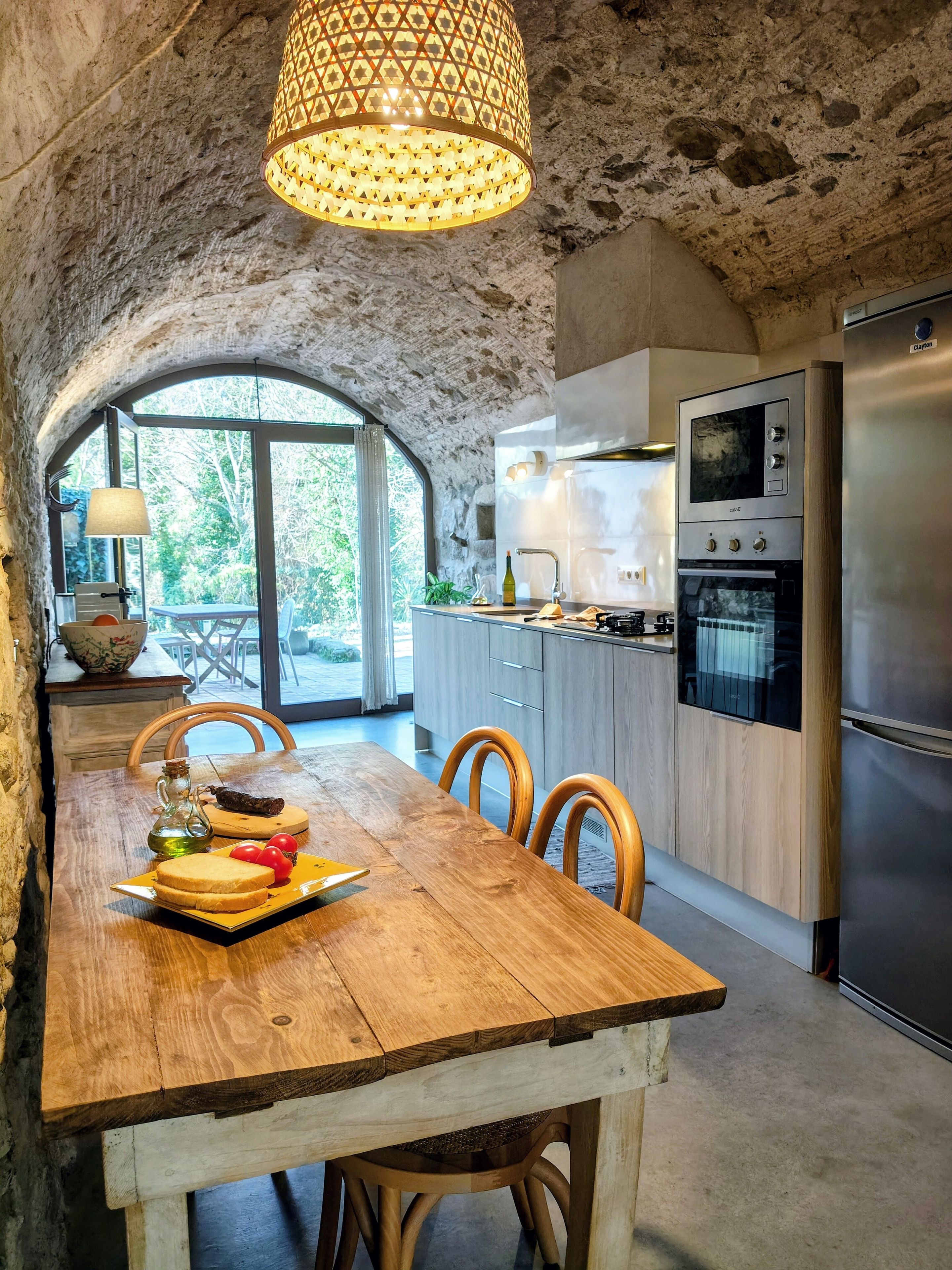 Une cuisine rustique avec une arche en pierre, une table à manger en bois et des appareils électroménagers modernes.
