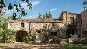 Un bâtiment en pierre avec un toit en tuiles, un balcon et des sièges à l’extérieur.