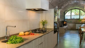 Une cuisine moderne équipée d’une cuisinière à gaz, d’un évier et d’une arche en pierre qui mène à un coin repas.