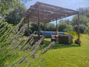 Un jardín con pérgola, mobiliario exterior y piscina.