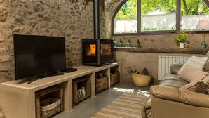 Une pièce aux murs de pierre, dotée d’une cheminée, d’un téléviseur et d’un canapé.