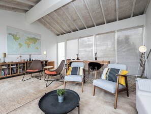 A spacious living room with a high ceiling, a world map on the wall, and a large window with sheer curtains. - Olea Brown Studio 3, Tavira, Algarve (Querença)