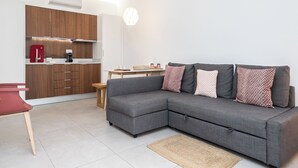 Ein modernes Wohnzimmer mit einem grauen Ecksofa, einem kleinen Holztisch und einem roten Sessel.