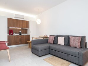 A modern living room with a grey sectional sofa, a small wooden table, and a red chair. - Olea Brown Studio 3, Tavira, Algarve (Querença)