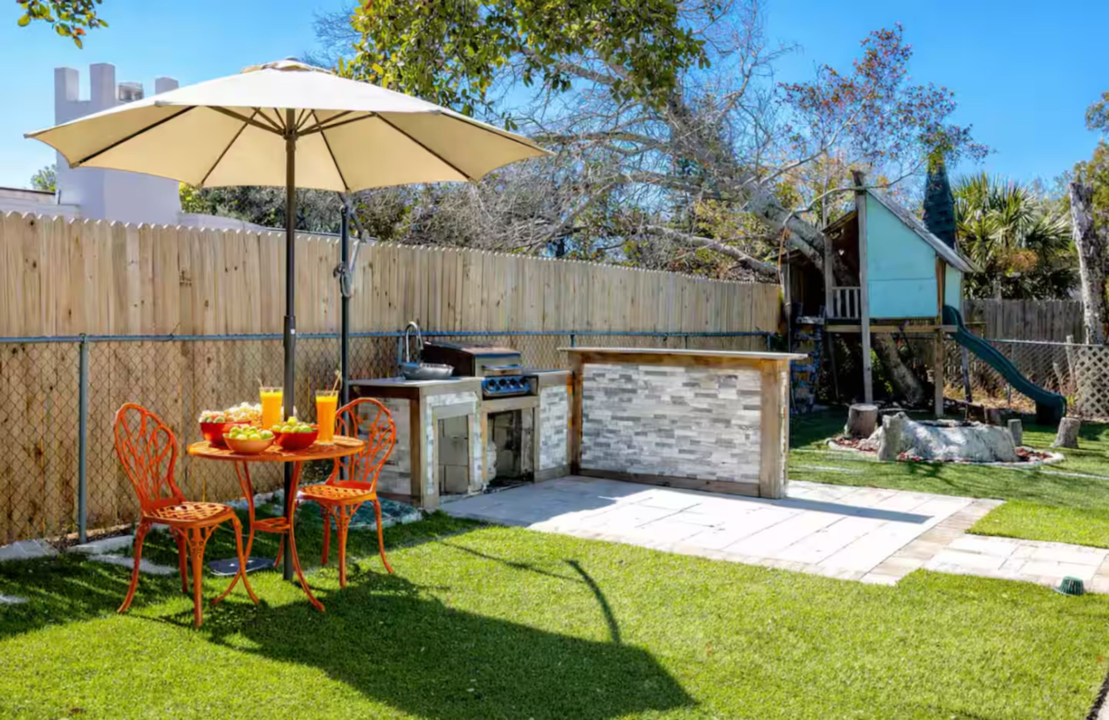 A backyard with a barbecue area, outdoor seating, and a play structure.