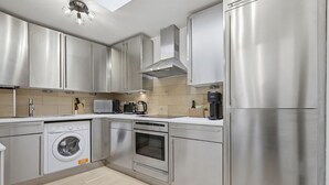 Une cuisine moderne équipée d’appareils électroménagers en acier inoxydable, d’un four encastré et d’un four à micro-ondes.